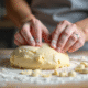 Mains de boulanger pétrissant pâte d'amande sur planche farinée